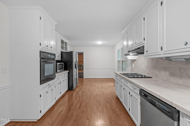5313 Falkirk Dr, Durham, NC 27712 - kitchen featuring black appliances, tile counters, under cabinet range hood, and white cabinetry
