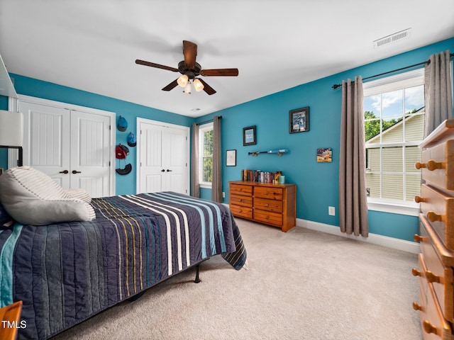 171 Winding Oak Way, Clayton, NC 27520 - carpeted bedroom with multiple closets, multiple windows, and a ceiling fan