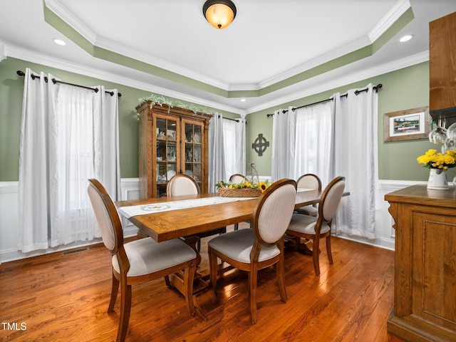 171 Winding Oak Way, Clayton, NC 27520 - dining room featuring a raised ceiling, a wainscoted wall, ornamental molding, light wood-type flooring, and a decorative wall