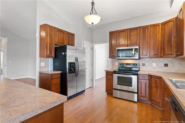 1605 Stanford Ct, Fayetteville, NC 28314 - kitchen with appliances with stainless steel finishes, light wood finished floors, tasteful backsplash, hanging light fixtures, and light countertops