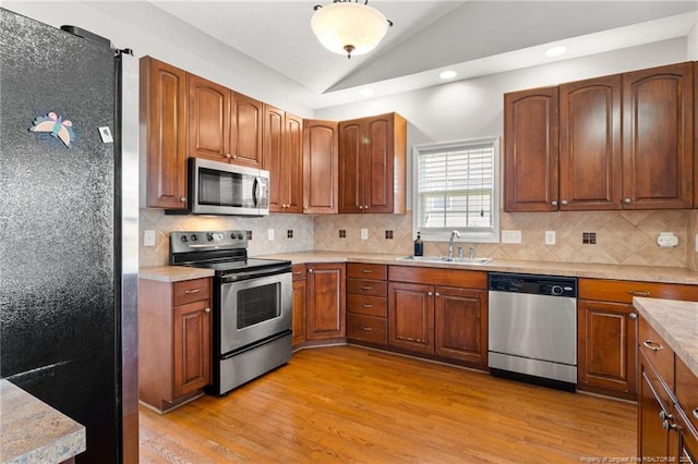 1605 Stanford Ct, Fayetteville, NC 28314 - kitchen with stainless steel appliances, lofted ceiling, light wood finished floors, light countertops, and tasteful backsplash