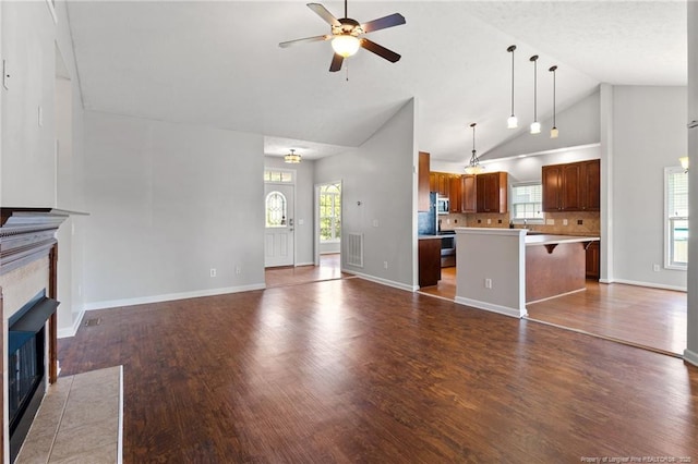 1605 Stanford Ct, Fayetteville, NC 28314 - unfurnished living room featuring a tiled fireplace, ceiling fan, wood finished floors, healthy amount of natural light, and high vaulted ceiling