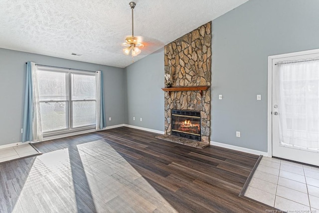 4105 Freedom Ln, Hope Mills, NC 28348 - unfurnished living room featuring a ceiling fan, a stone fireplace, wood finished floors, a textured ceiling, and vaulted ceiling
