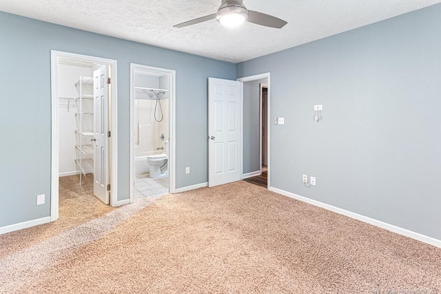 4105 Freedom Ln, Hope Mills, NC 28348 - unfurnished bedroom featuring carpet flooring, a walk in closet, a closet, ensuite bath, and a textured ceiling