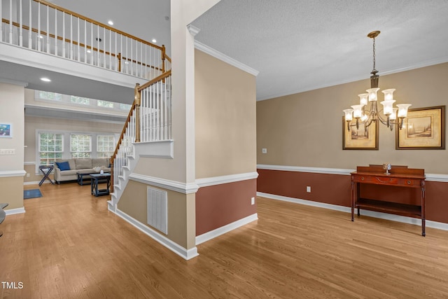 3608 Smoky Chestnut Ln, Raleigh, NC 27615 - stairs featuring wood finished floors, crown molding, a chandelier, and a textured ceiling