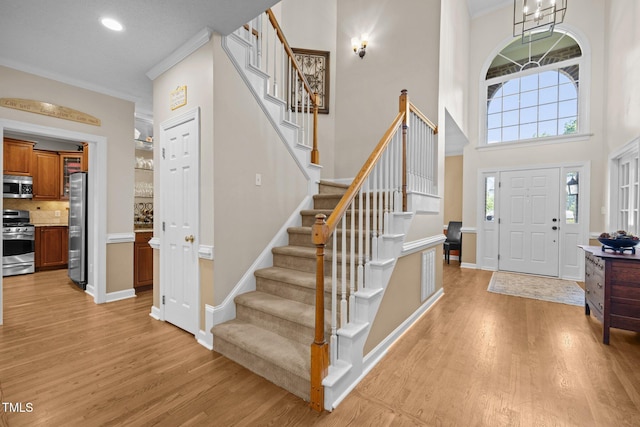 3608 Smoky Chestnut Ln, Raleigh, NC 27615 - entrance foyer with light wood-type flooring, stairs, crown molding, a towering ceiling, and recessed lighting
