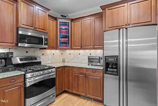 3608 Smoky Chestnut Ln, Raleigh, NC 27615 - kitchen featuring appliances with stainless steel finishes, crown molding, light stone counters, light wood-type flooring, and glass insert cabinets