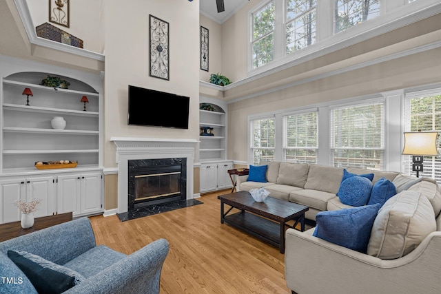 3608 Smoky Chestnut Ln, Raleigh, NC 27615 - living area featuring built in shelves, a towering ceiling, healthy amount of natural light, light wood-type flooring, and ornamental molding