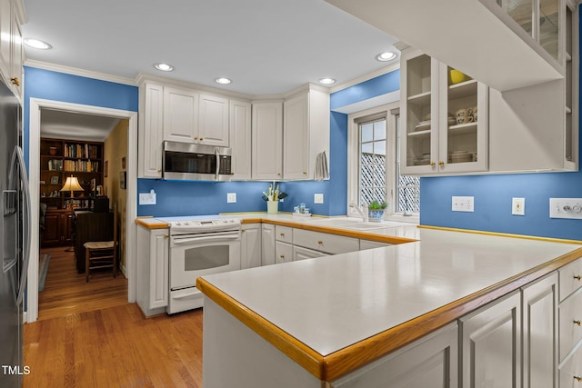 906 Grove St, Chapel Hill, NC 27517 - kitchen featuring stainless steel appliances, white cabinetry, light countertops, ornamental molding, and light wood-style floors