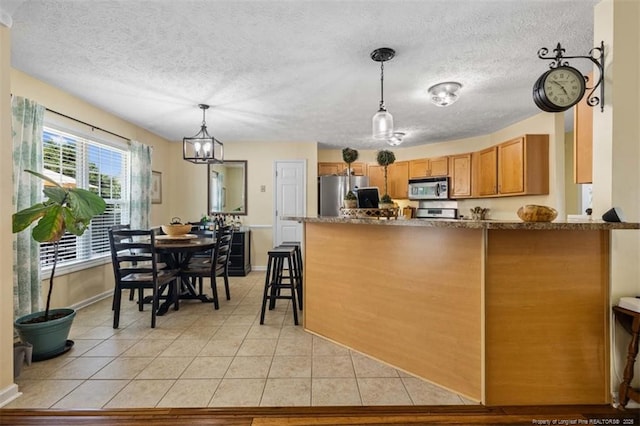3313 Geyser Peak Rd, Fayetteville, NC 28306 - kitchen with stainless steel appliances, a peninsula, a textured ceiling, hanging light fixtures, and light tile patterned flooring