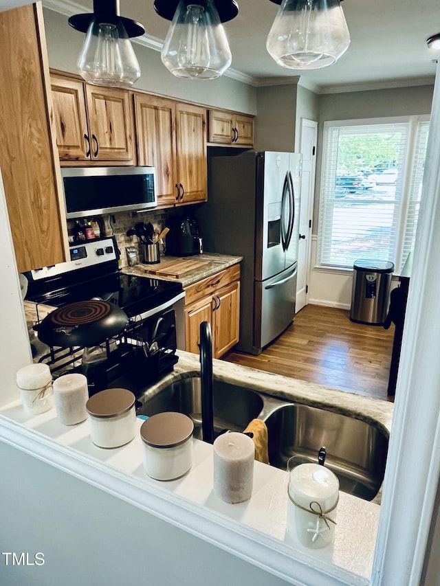 1507 Woodcroft Dr, Raleigh, NC 27609 - kitchen featuring stainless steel appliances, crown molding, brown cabinetry, wood finished floors, and tasteful backsplash