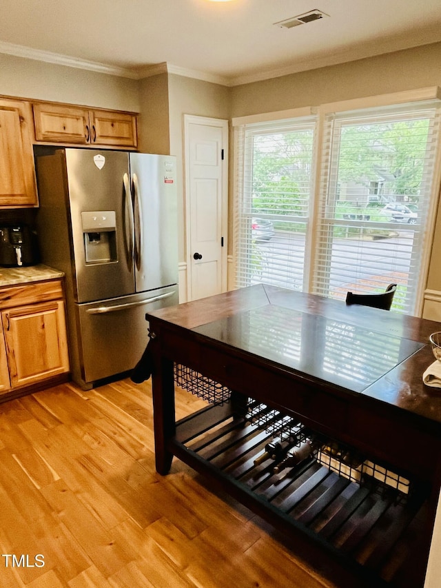 1507 Woodcroft Dr, Raleigh, NC 27609 - kitchen featuring stainless steel fridge with ice dispenser, light wood-type flooring, ornamental molding, brown cabinetry, and light countertops