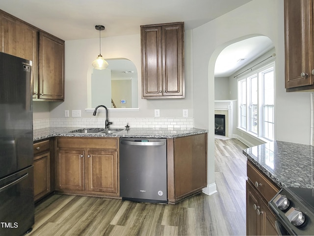 709 Pyracantha Dr, Holly Springs, NC 27540 - kitchen with stainless steel dishwasher, freestanding refrigerator, arched walkways, and wood finished floors