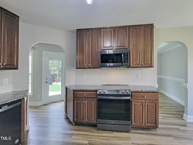 709 Pyracantha Dr, Holly Springs, NC 27540 - kitchen featuring appliances with stainless steel finishes, stone counters, arched walkways, light wood-style flooring, and recessed lighting