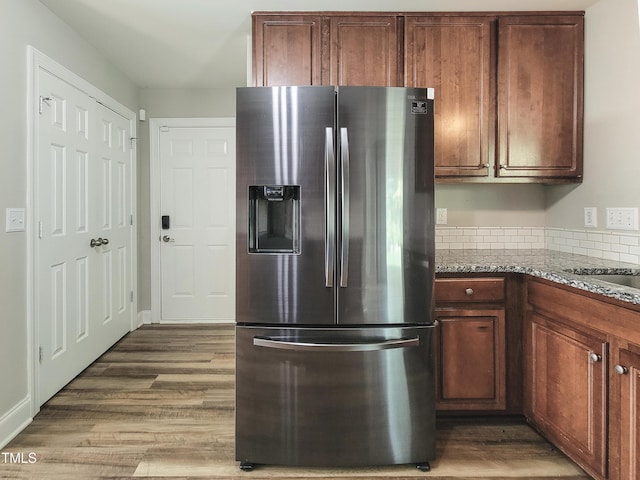 709 Pyracantha Dr, Holly Springs, NC 27540 - kitchen with stainless steel refrigerator with ice dispenser, wood finished floors, light stone counters, and tasteful backsplash