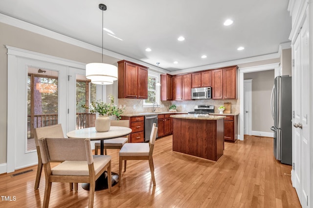 4324 Brighton Ridge Dr, Apex, NC 27539 - kitchen with stainless steel appliances, crown molding, a kitchen island, backsplash, and light wood finished floors