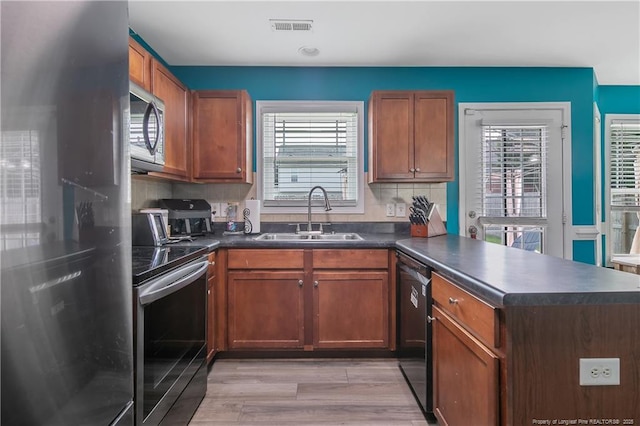 1214 Herring Gull Dr, Fayetteville, NC 28306 - kitchen with stainless steel appliances, dark countertops, a peninsula, light wood-style flooring, and backsplash