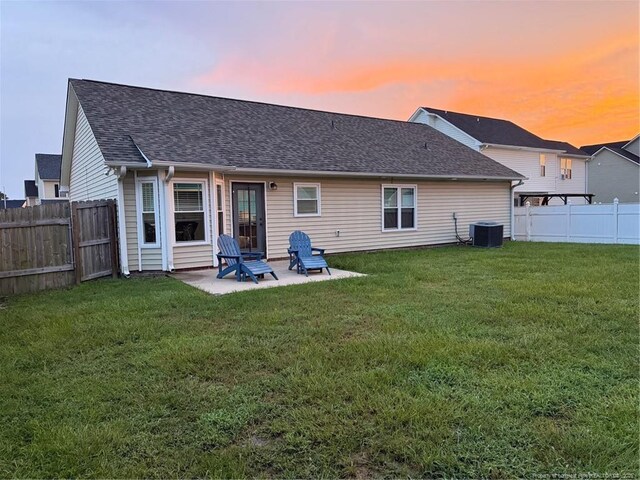 1214 Herring Gull Dr, Fayetteville, NC 28306 - back of house at dusk featuring a fenced backyard, a patio area, and a shingled roof