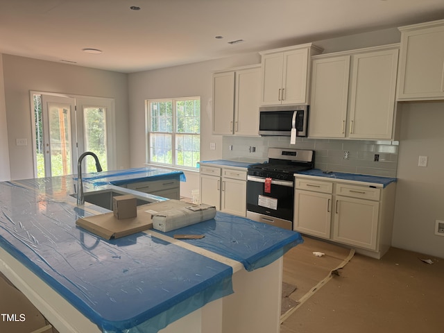 5486 Jaeger Dr Lot # 37, Graham, NC 27253 - kitchen featuring stainless steel appliances, a kitchen island with sink, backsplash, and white cabinetry