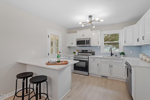 3408 Brentwood Rd, Raleigh, NC 27604 - kitchen with stainless steel appliances, a kitchen breakfast bar, a peninsula, light wood finished floors, and decorative backsplash