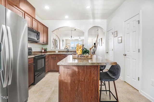 100 Stratford Lakes Dr # 322, Durham, NC 27713 - kitchen with black appliances, arched walkways, a breakfast bar, a kitchen island, and recessed lighting