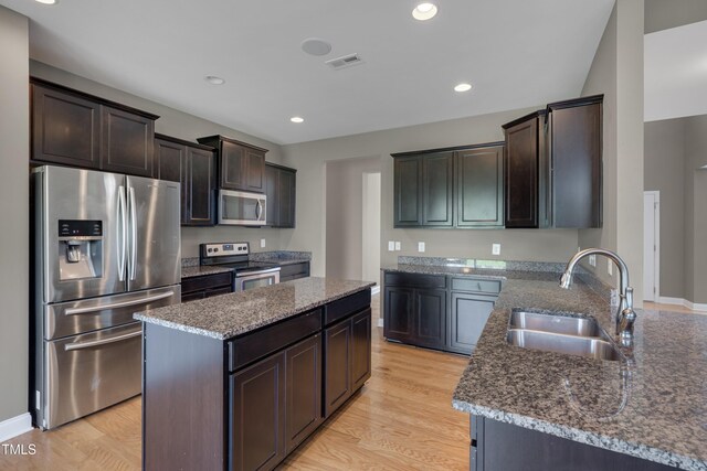 615 Fairway Dr, Mebane, NC 27302 - kitchen with appliances with stainless steel finishes, dark stone counters, dark brown cabinets, light wood finished floors, and a kitchen island