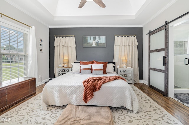 305 Maddux Dr, Pikeville, NC 27863 - bedroom featuring a barn door, a raised ceiling, wood finished floors, multiple windows, and ornamental molding