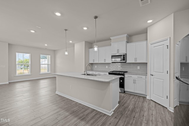 348 Abbots Mill Dr, Raleigh, NC 27603 - kitchen with appliances with stainless steel finishes, decorative backsplash, white cabinets, wood finished floors, and an island with sink