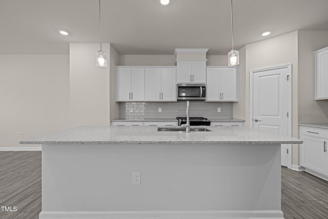 348 Abbots Mill Dr, Raleigh, NC 27603 - kitchen with stainless steel microwave, a center island with sink, white cabinets, and recessed lighting