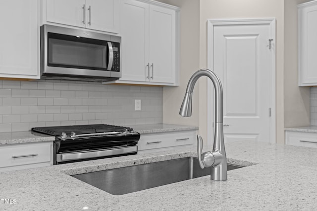 348 Abbots Mill Dr, Raleigh, NC 27603 - kitchen featuring appliances with stainless steel finishes, white cabinets, backsplash, and light stone countertops