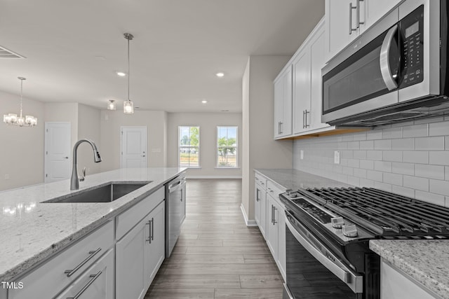 348 Abbots Mill Dr, Raleigh, NC 27603 - kitchen featuring stainless steel appliances, light wood-style flooring, decorative backsplash, white cabinetry, and pendant lighting