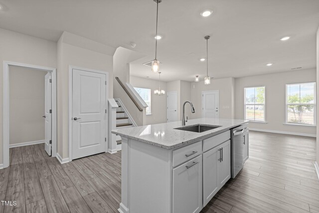 348 Abbots Mill Dr, Raleigh, NC 27603 - kitchen with dishwasher, light wood finished floors, light stone counters, hanging light fixtures, and an island with sink