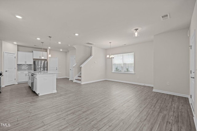 348 Abbots Mill Dr, Raleigh, NC 27603 - kitchen with light countertops, freestanding refrigerator, white cabinets, backsplash, and light wood-style floors