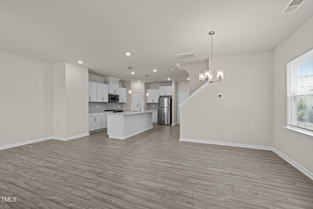 348 Abbots Mill Dr, Raleigh, NC 27603 - kitchen with open floor plan, stainless steel appliances, a chandelier, light countertops, and light wood finished floors