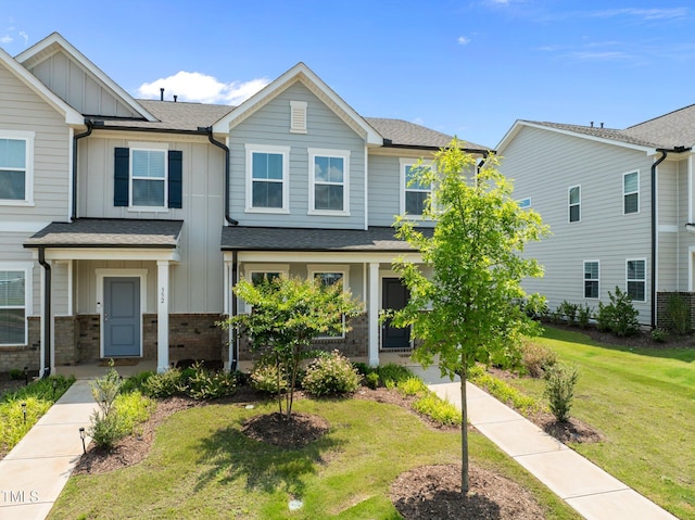 348 Abbots Mill Dr, Raleigh, NC 27603 - townhome / multi-family property with board and batten siding, a front lawn, roof with shingles, and brick siding