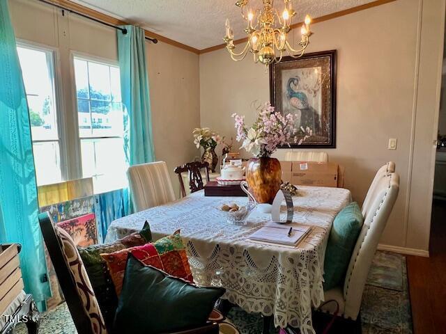 174 Daffodil Dr, Henderson, NC 27537 - dining area featuring crown molding, a chandelier, wood finished floors, and a textured ceiling
