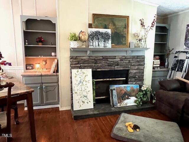 174 Daffodil Dr, Henderson, NC 27537 - living room with a stone fireplace, crown molding, and dark wood-style flooring