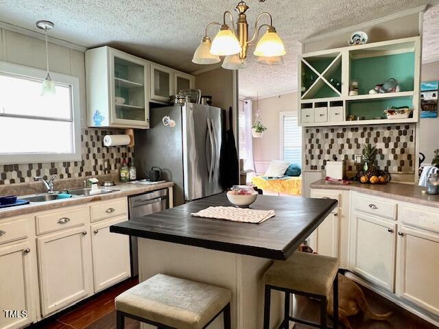 174 Daffodil Dr, Henderson, NC 27537 - kitchen featuring a textured ceiling, a chandelier, plenty of natural light, decorative backsplash, and crown molding