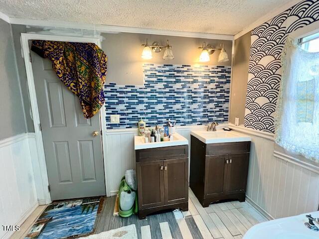 174 Daffodil Dr, Henderson, NC 27537 - full bath with a textured ceiling, vanity, wood finished floors, wainscoting, and crown molding
