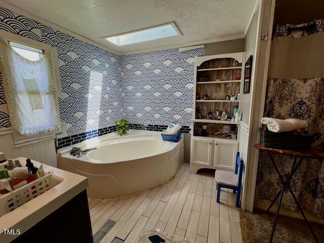 174 Daffodil Dr, Henderson, NC 27537 - full bathroom with a garden tub, vanity, a textured ceiling, ornamental molding, and wood finished floors