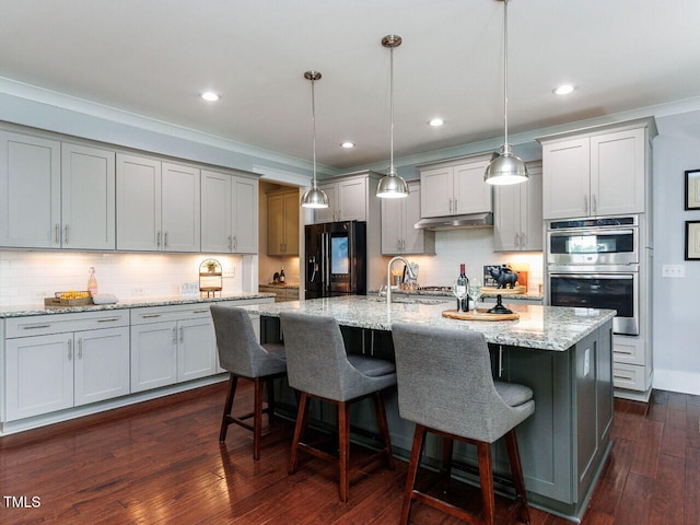 8712 Halsey Ln, Wake Forest, NC 27587 - kitchen with black fridge, stainless steel double oven, tasteful backsplash, under cabinet range hood, and a kitchen breakfast bar
