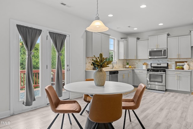 837 Stable Fern Dr, Fuquay Varina, NC 27526 - kitchen featuring stainless steel appliances, light countertops, tasteful backsplash, light wood-style flooring, and decorative light fixtures