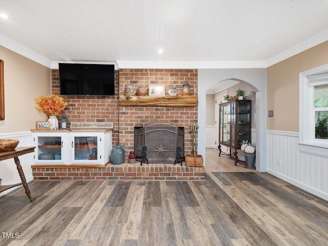 358 Benjie Williams Rd, Staley, NC 27355 - living area with ornamental molding, wood finished floors, a fireplace, a wainscoted wall, and arched walkways