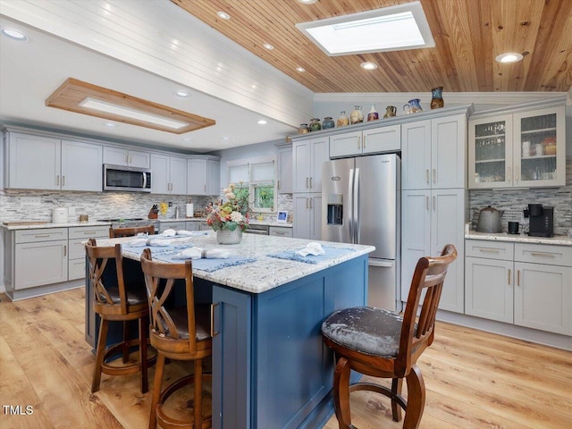 358 Benjie Williams Rd, Staley, NC 27355 - kitchen with appliances with stainless steel finishes, a skylight, a breakfast bar, decorative backsplash, and a kitchen island
