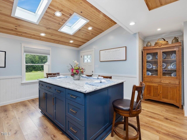 358 Benjie Williams Rd, Staley, NC 27355 - kitchen featuring a wainscoted wall, a skylight, blue cabinets, light wood-style flooring, and ornamental molding