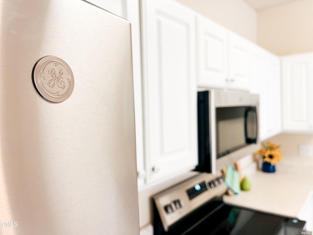 2520 Friedland Pl Unit 200, Raleigh, NC 27617 - kitchen view of range with electric cooktop, stainless steel microwave, white cabinetry, and light countertops