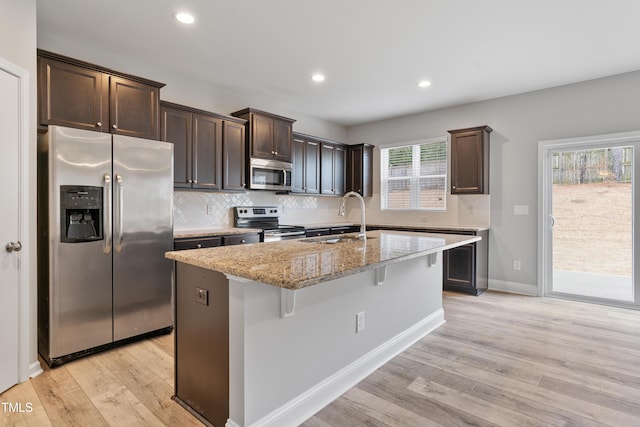 165 Naples Ln, Clayton, NC 27527 - kitchen with appliances with stainless steel finishes, dark brown cabinets, light wood finished floors, light stone counters, and recessed lighting