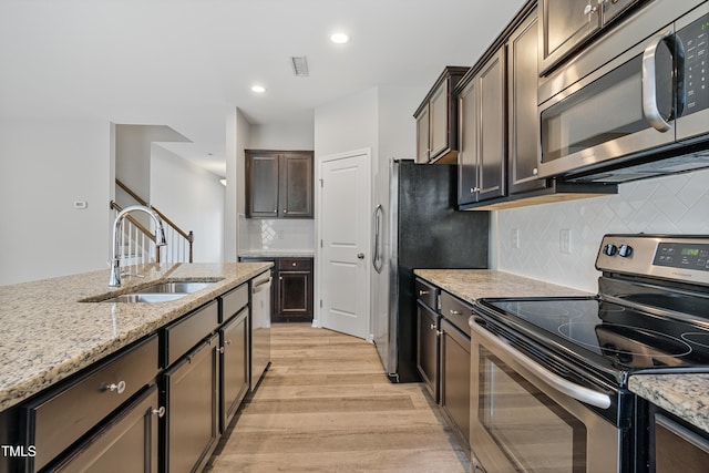 165 Naples Ln, Clayton, NC 27527 - kitchen featuring appliances with stainless steel finishes, light wood-style flooring, dark brown cabinets, light stone counters, and tasteful backsplash