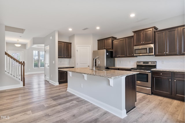 165 Naples Ln, Clayton, NC 27527 - kitchen featuring stainless steel appliances, dark brown cabinetry, light wood finished floors, a kitchen breakfast bar, and recessed lighting