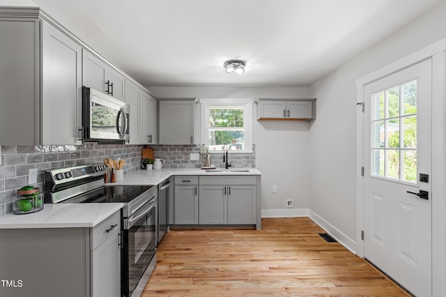 833 Brigham Rd, Raleigh, NC 27610 - kitchen with stainless steel appliances, gray cabinets, backsplash, and light wood finished floors
